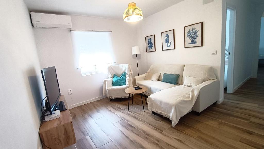 a living room with a white couch and a television at Puerto Placilla in El Puerto de Santa María