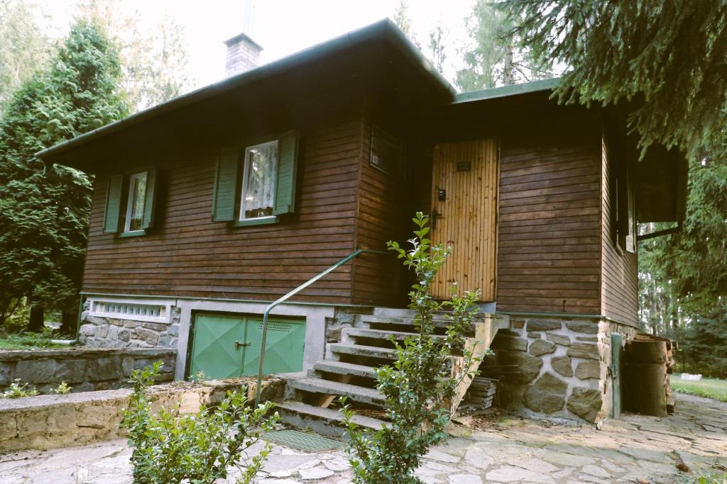 a wooden house with a green door and stairs at Chata Skřinářov 