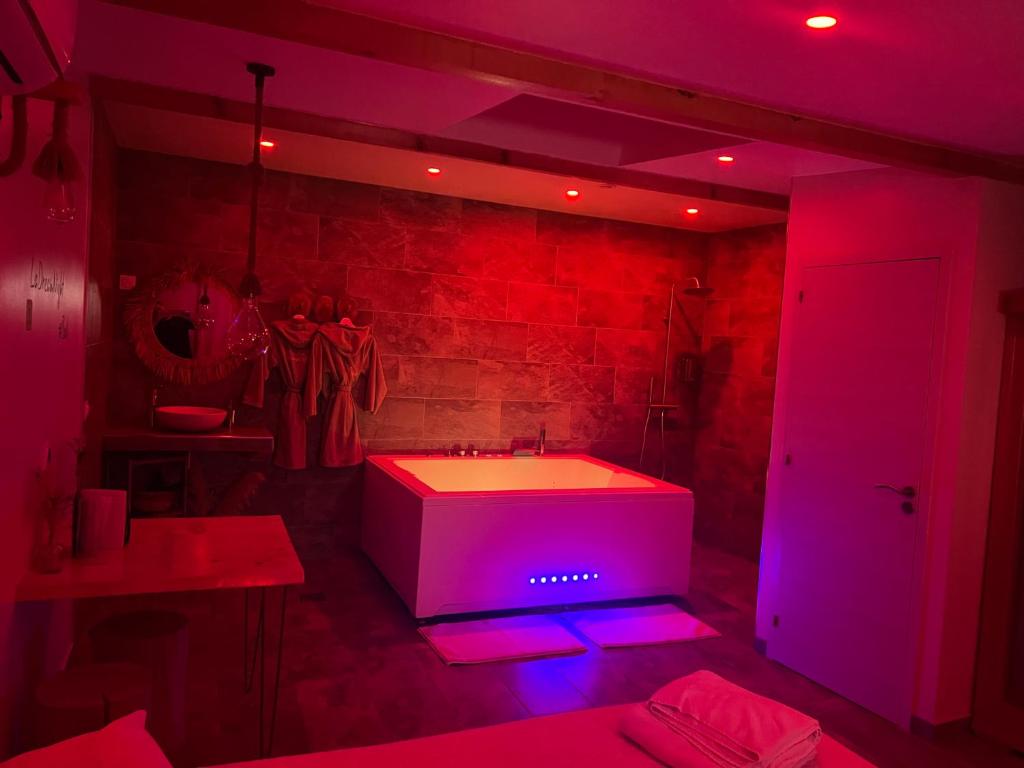 uma casa de banho com uma banheira branca e luzes roxas em La Dream Night em Pontault-Combault