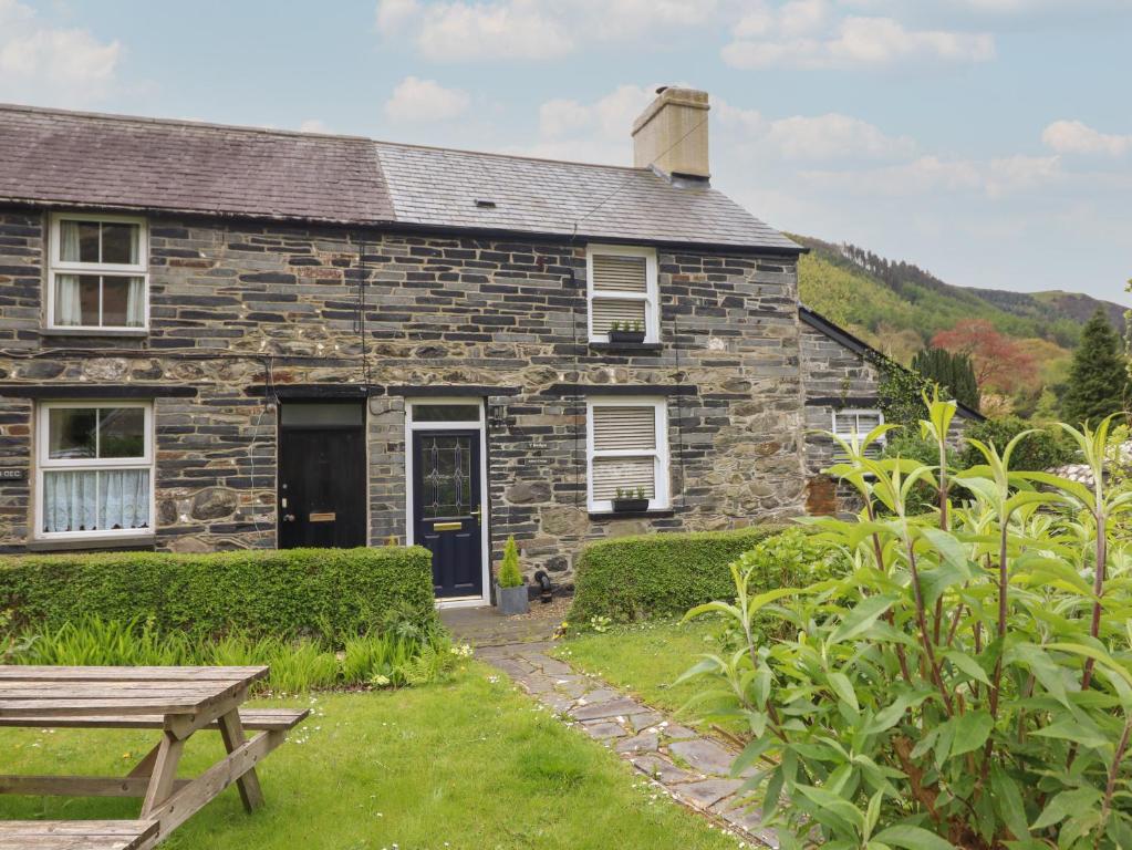 a stone house with a picnic table in front of it at Arthurs Cottage in Tywyn