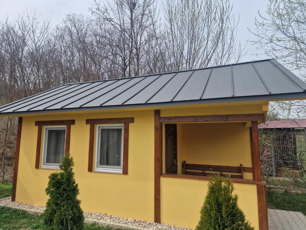 a small yellow house with a black roof at Cabanute Maya Transalpina in Săsciori