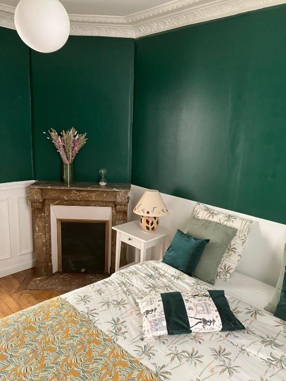 - une chambre verte avec un lit et une cheminée dans l'établissement Cosy appartement in Paris, à Paris