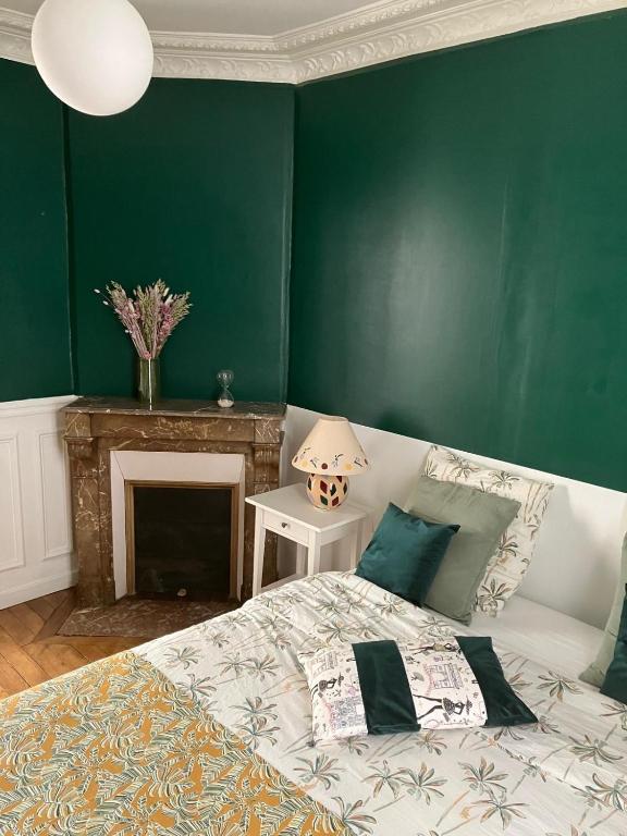 a green bedroom with a bed and a fireplace at Cosy appartement in Paris in Paris