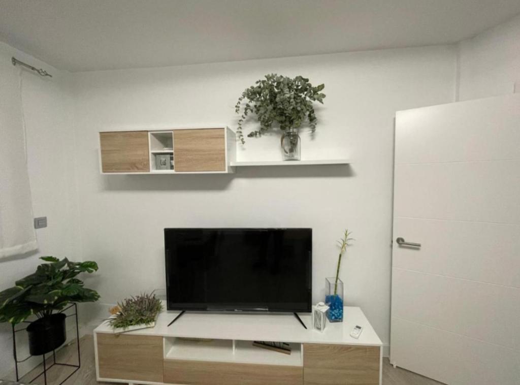 een woonkamer met een flatscreen-tv aan een witte muur bij Apartamento nuevo en Puertollano in Puertollano