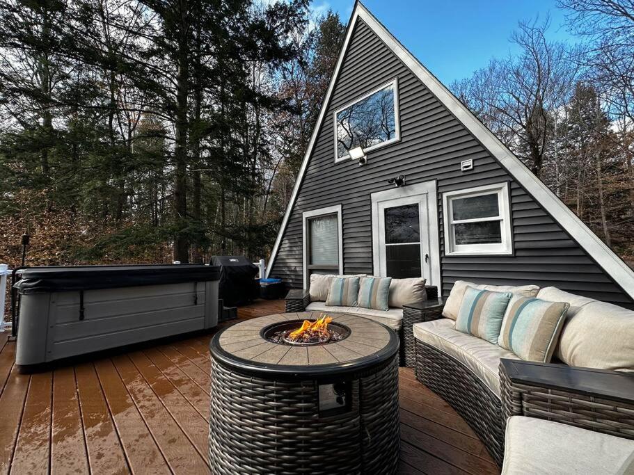 a backyard patio with a fire pit and a house at NEW! Cozy & Modern A-Frame in the woods w/HOT TUB in Tamworth