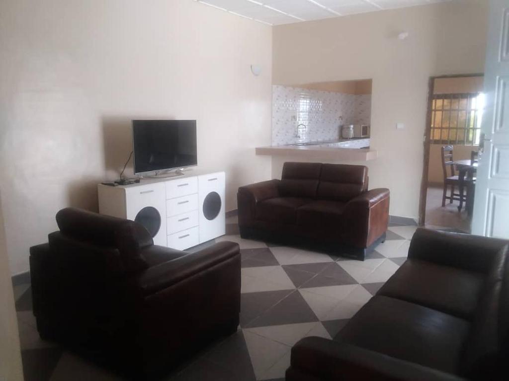 ein Wohnzimmer mit 2 Sofas und einem TV in der Unterkunft Fidjrossé Beach in Cotonou