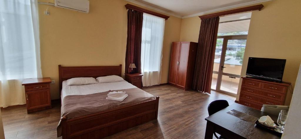 SWEET HOME HOTEL Meghri في Meghri: غرفة نوم بسرير ومكتب وتلفزيون