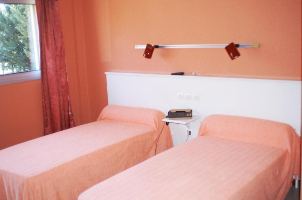 deux lits dans une chambre aux murs orange dans l'établissement Le Pré Fleuri, à Dax