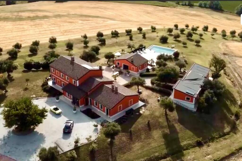 an aerial view of a large red house with a pool at Agriturismo il maniero in Ancona