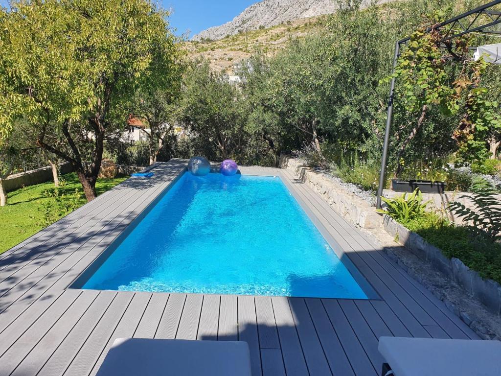 a swimming pool in a backyard with a wooden deck at Great 4-bedroom villa w heated eco pool in Duće