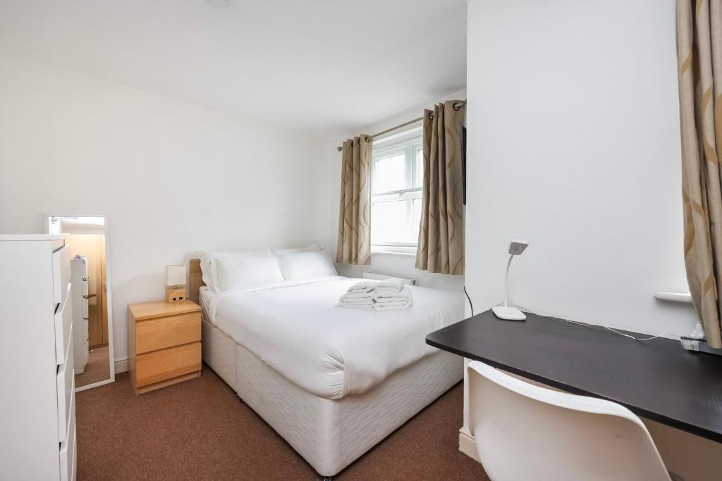 a bedroom with a white bed and a desk at Vibrant Clapham Double bedroom in London