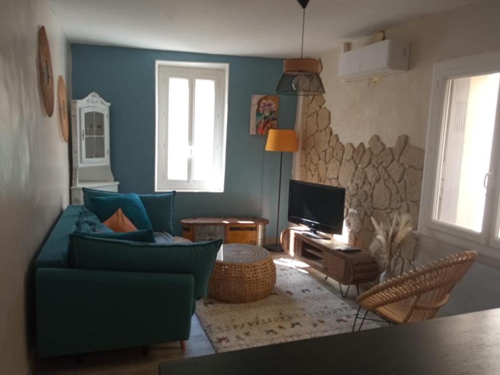 un salon avec un canapé bleu et une télévision dans l'établissement Maison de village Sarrians, à Sarrians