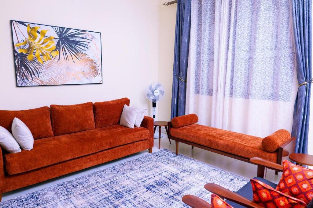 een woonkamer met een bank en 2 stoelen bij Ahva II Residence in Jinja
