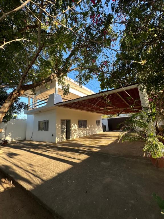 une grande maison blanche avec des arbres devant elle dans l'établissement Bonita Casa de Campo en Celestino Gasca, à Celestino Gasca