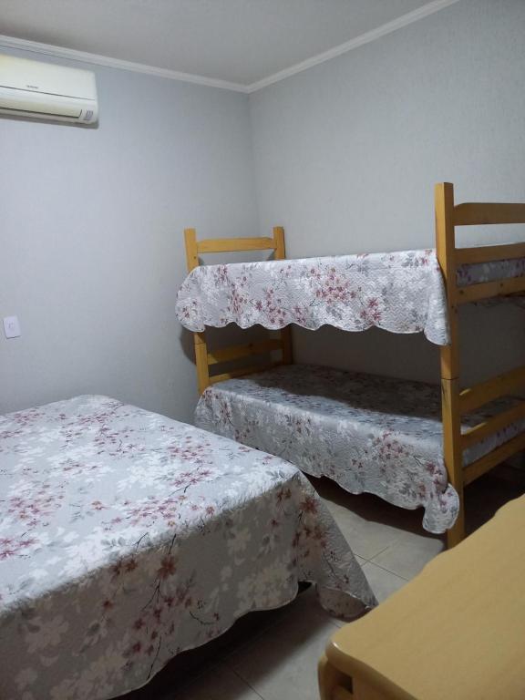 a room with two beds and a chair with a table at Chácara Santa Rita in Bom Jesus dos Perdões