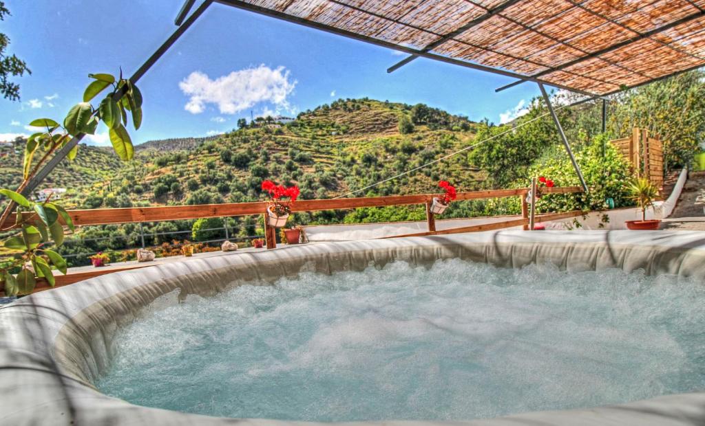 uma banheira de hidromassagem exterior com vista para uma montanha em Finca el Almendro Archez em Árchez