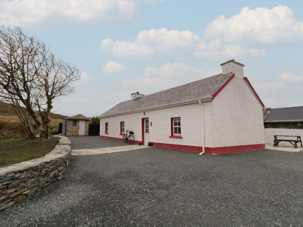 a white and red building with a stone wall at Teach Phaidí Mhóir in Donegal
