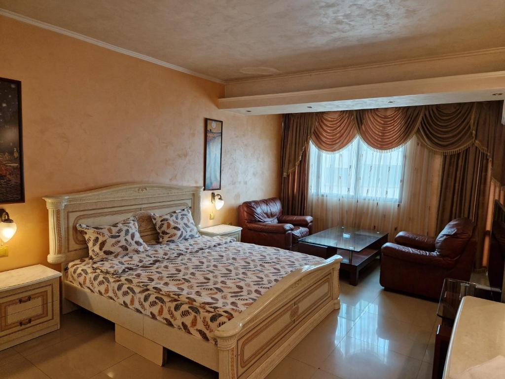 una camera con un grande letto e due sedie di Хотел-ресторант Астория a Pazardžik