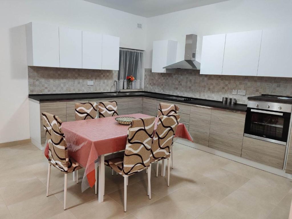 a kitchen with a table and chairs and white cabinets at Star Dream Apartment in Xgħajra