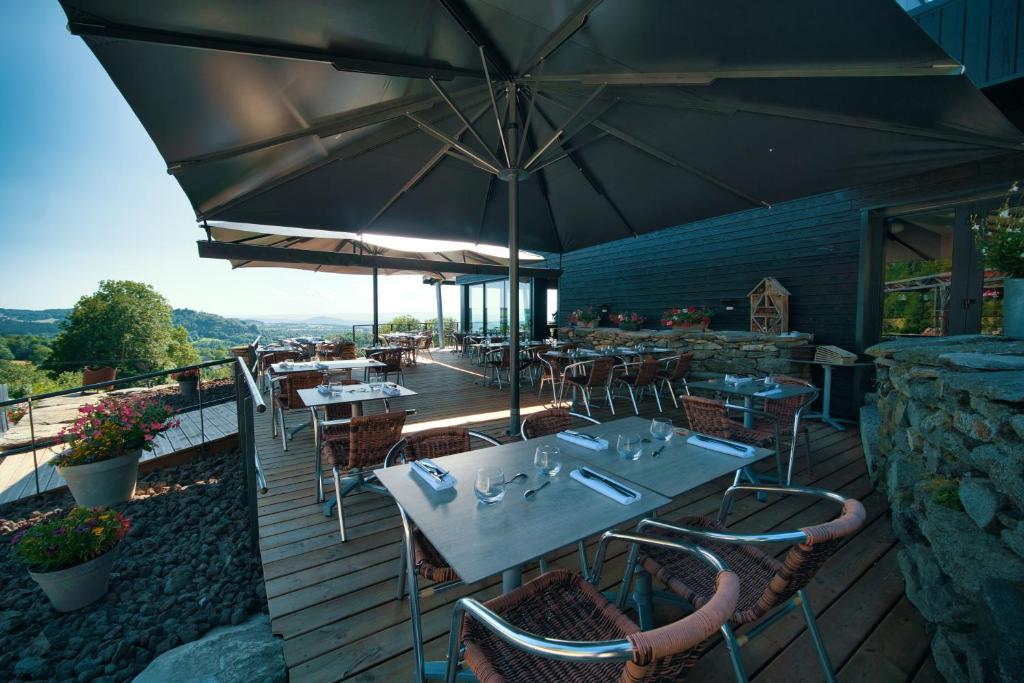a restaurant with tables and chairs and an umbrella at La Ferme du Bien-etre in Saint-Julien-Chapteuil