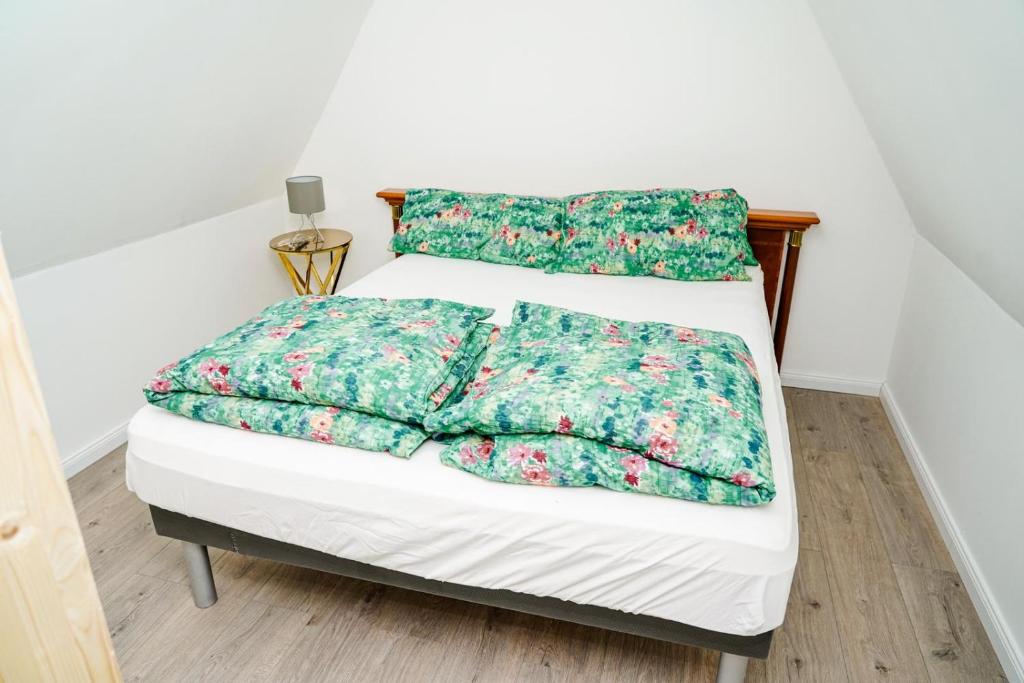 a bed with green comforter and two pillows at Holiday Dream House-B for 6 Persons in Tornesch