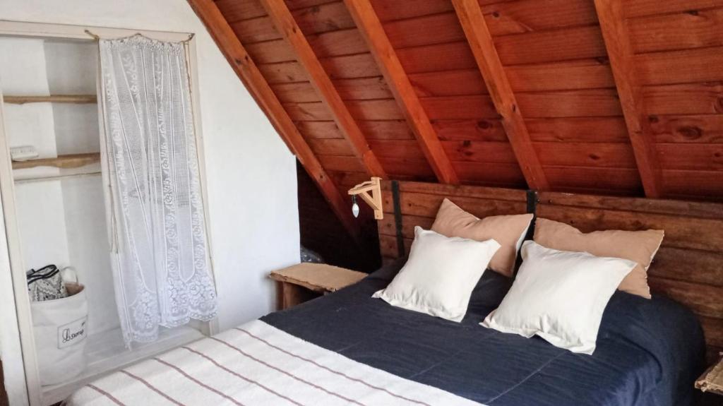 1 dormitorio con cama y techo de madera en Cabaña,Chalet Alpino Bosques de Peralta Ramos en Mar del Plata
