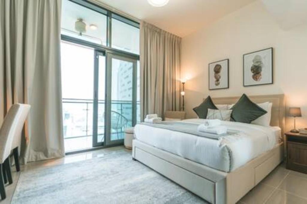 a bedroom with a large bed and a large window at Gorgeous Apt Studio with balcony in Business Bay in Dubai