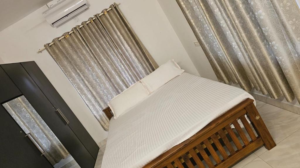 uma pequena cama num quarto com cortinas em Peaceful homes em Thrissur