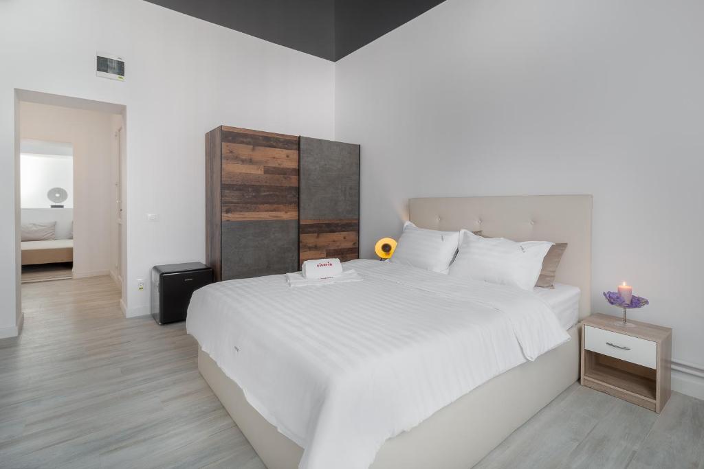 een slaapkamer met een groot wit bed met een houten hoofdeinde bij VIVERIA in Oradea