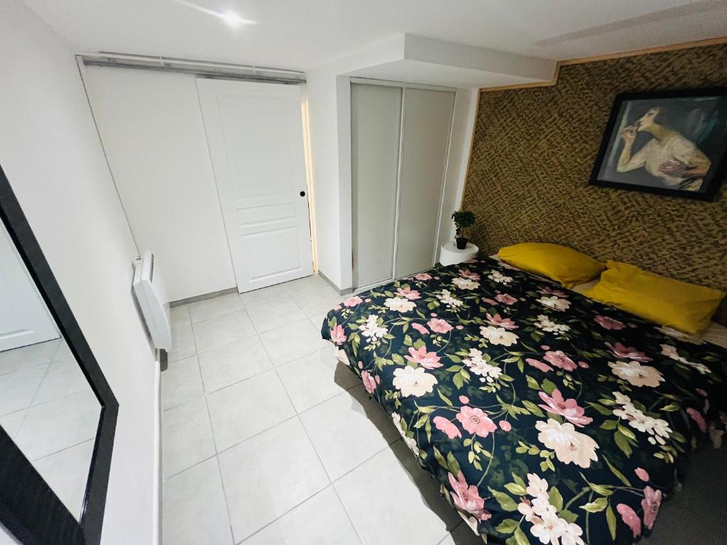 - une chambre dotée d'un lit avec un couvre-lit floral dans l'établissement VILLA LINDA, à Tremblay-en-France