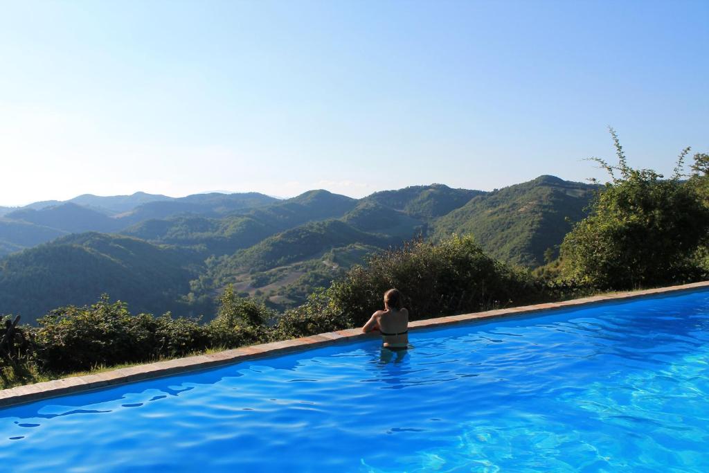 una mujer sentada en una piscina con vistas a las montañas en Country House Il Biroccio en Urbino