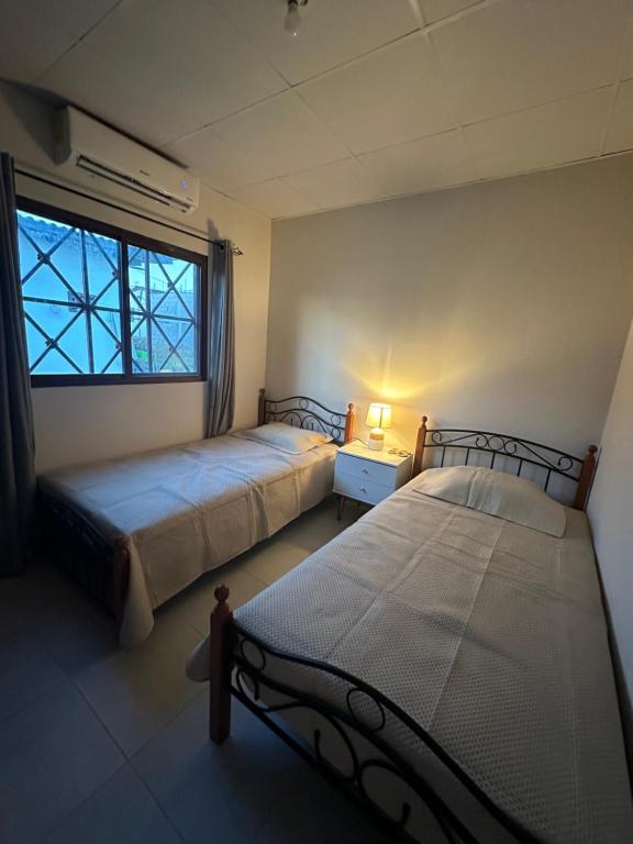 2 Betten in einem Zimmer mit Fenster in der Unterkunft Mi casa es su casa at Villas de Santamaría in Penonomé