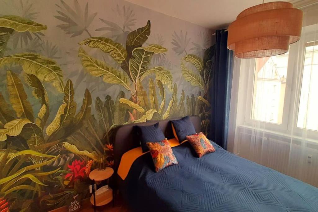 1 dormitorio con cama azul y papel pintado tropical en Apartment Botanica en Zvolen