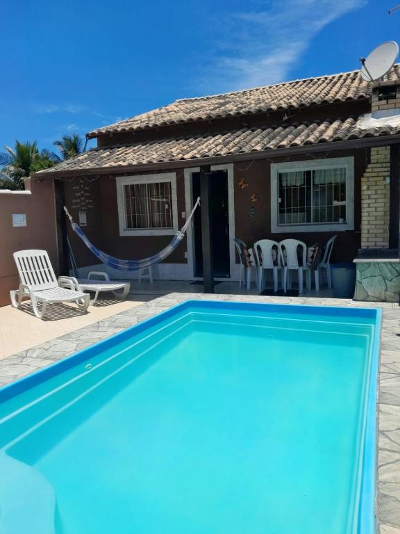 a blue swimming pool in front of a house at Meu lugar de Descanso in Cabo Frio
