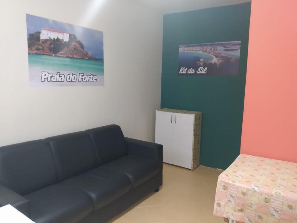 een woonkamer met een zwarte bank en een tafel bij KIT DA SIL in Cabo Frio