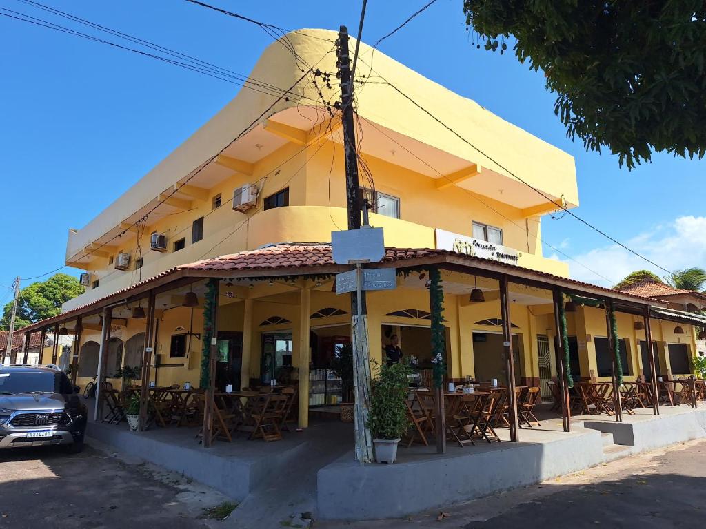 ein gelbes Gebäude mit Tischen und Stühlen davor in der Unterkunft HOTEL E RESTAURANTE ILHA BELA in Soure