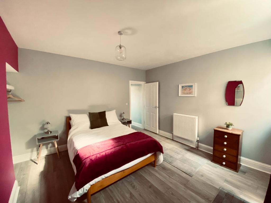 a bedroom with a bed with a red blanket at Tideway Apartment with Private Parking Space in Whitby