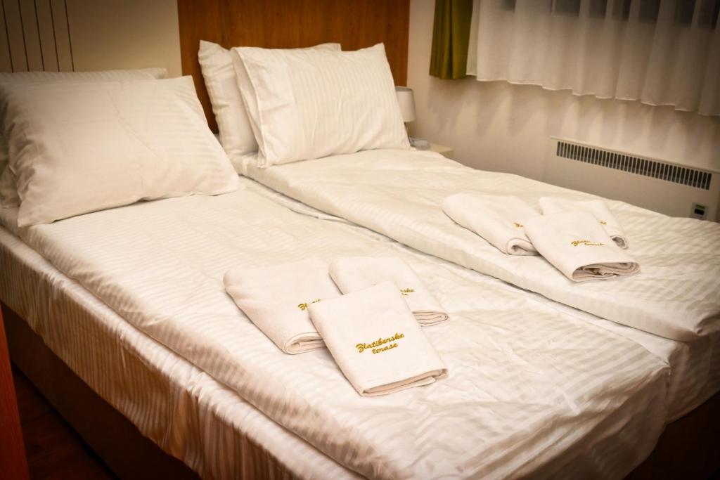 a bed with white towels and pillows on it at Zlatibor apartman in Zlatibor
