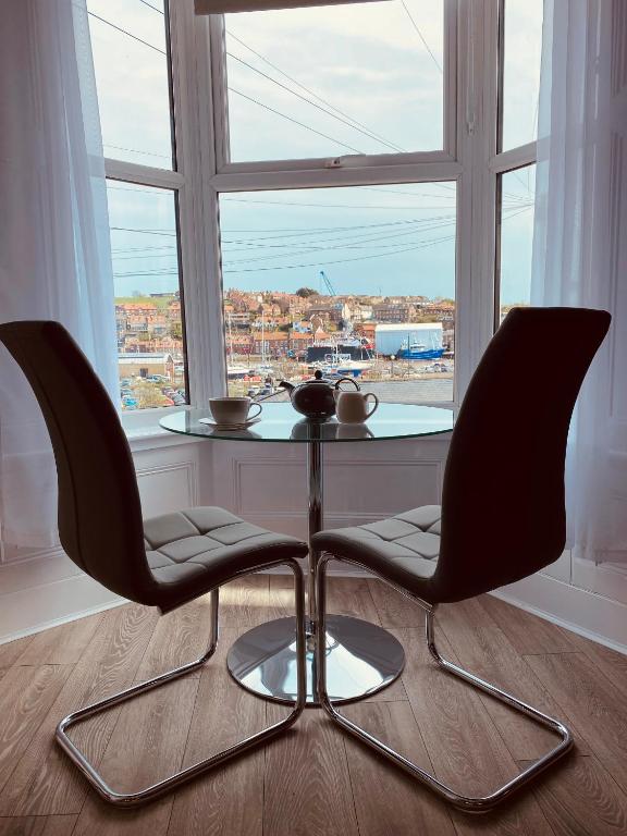 a table and two chairs in front of a window at Tideway Apartment with Private Parking Space in Whitby