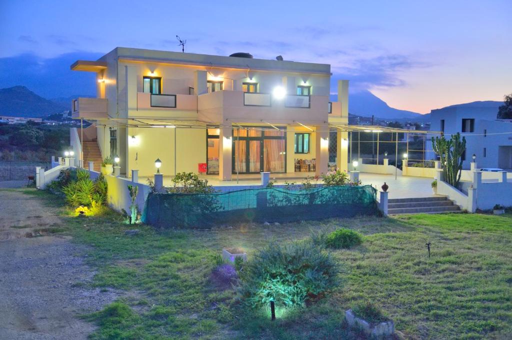 a large house with lights on in a yard at Girogiali Apts in Kissamos