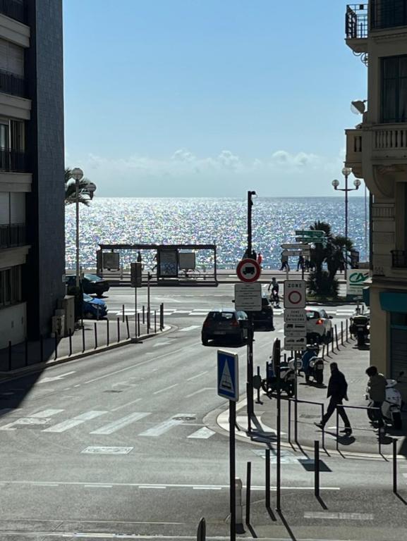 Une rue dans une ville avec l'océan en arrière-plan dans l'établissement Appartement avec vue mer, à Nice