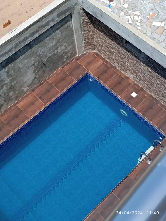 a large swimming pool with blue water and wooden floors at Luxe Villa in Cotonou