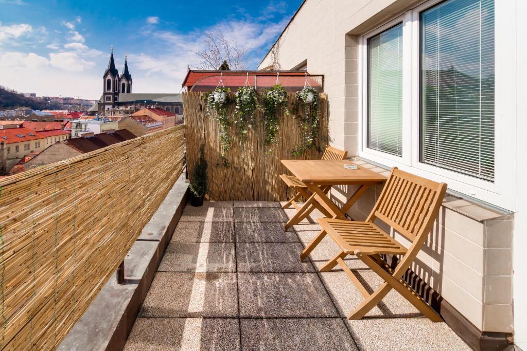 eine Terrasse mit einem Holztisch und Stühlen auf dem Balkon in der Unterkunft Top floor sunny studio with terrace in Prag