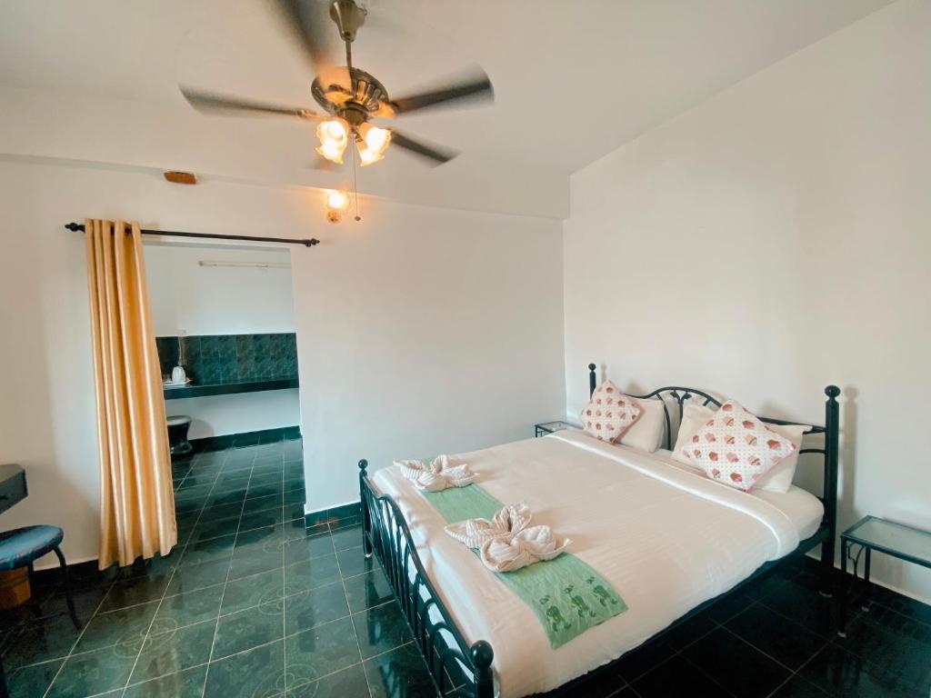 een slaapkamer met een bed met roze kussens en een plafondventilator bij Honeydew Suites and Villas by Goaround Homes in Vagator