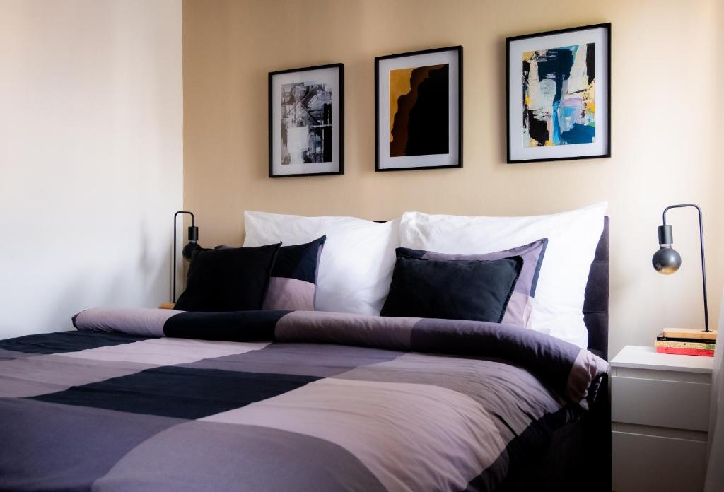 ein Schlafzimmer mit einem Bett mit vier Bildern an der Wand in der Unterkunft Cozy studio apartment in New Town with Disney+ in Prag