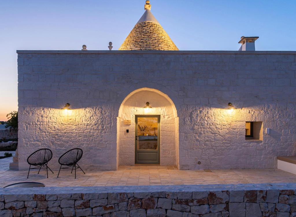 two chairs in front of a building with a door at Trullo Jalè - Boutique Apartments in Ostuni