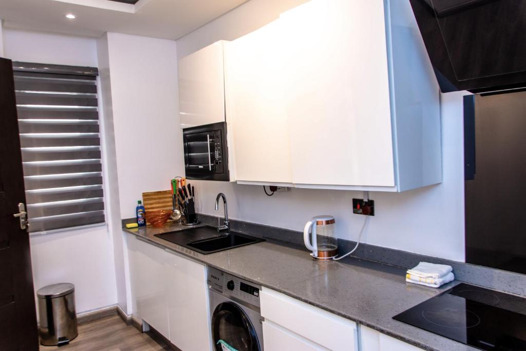 a kitchen with white cabinets and a sink and a microwave at Treasurablehomes in Lagos