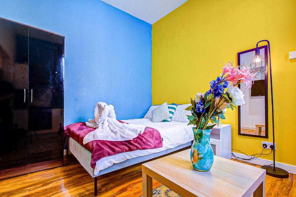Cette chambre comprend un lit avec une table et un vase de fleurs. dans l'établissement Cozy Apartments near Central Dubai, à Dubaï