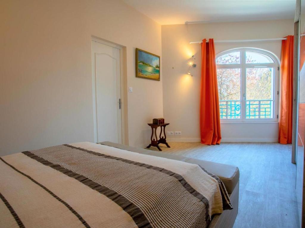 Le Celtic في دينارد: غرفة نوم مع سرير ونافذة مع ستائر برتقالية
