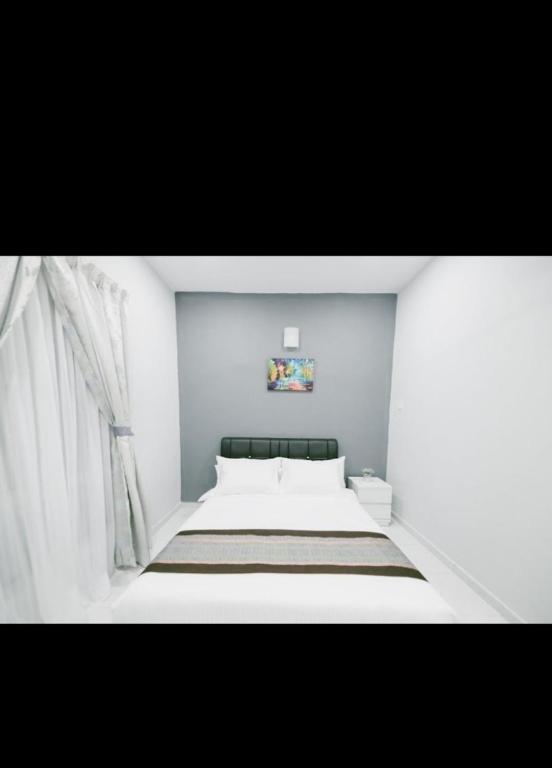 1 dormitorio con 1 cama grande y paredes blancas en Langkawi homestay en Pantai Cenang